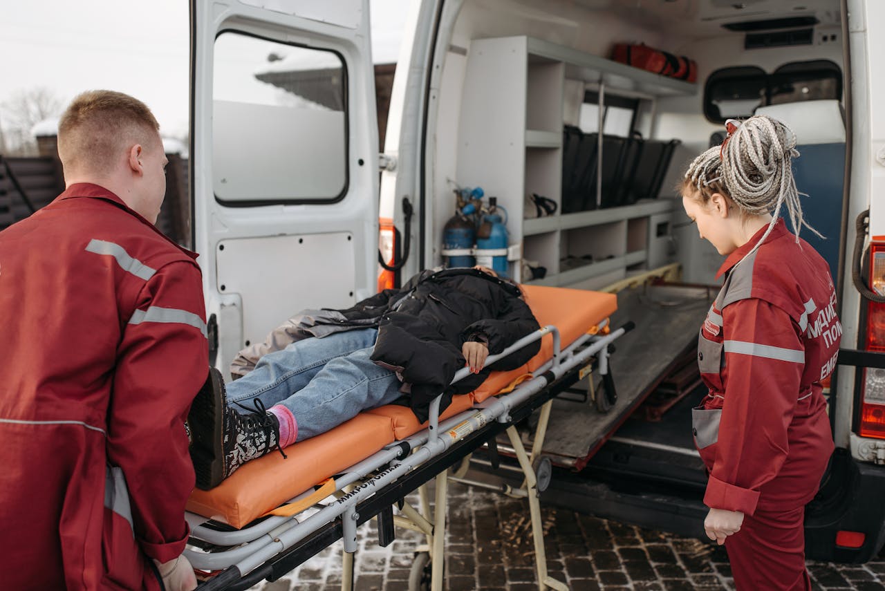 Paramedics loading a patient onto an ambulance stretcher for emergency transportation.